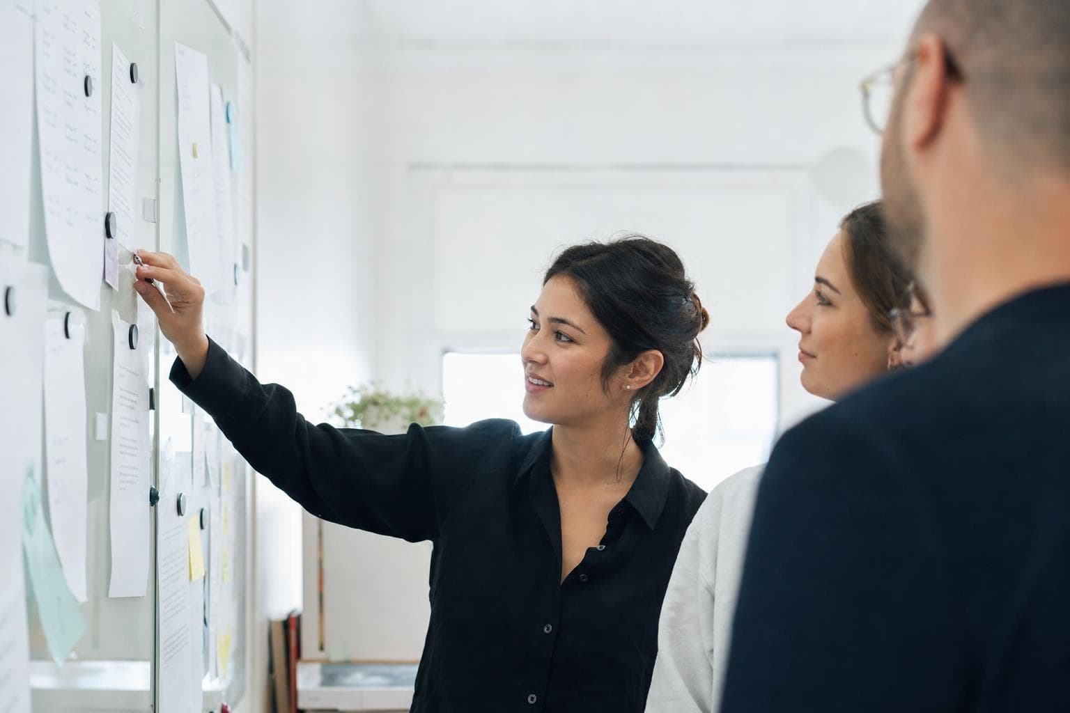 A photo of a small, calm team gathered around a shared task board in a bright office, work clearly organized.