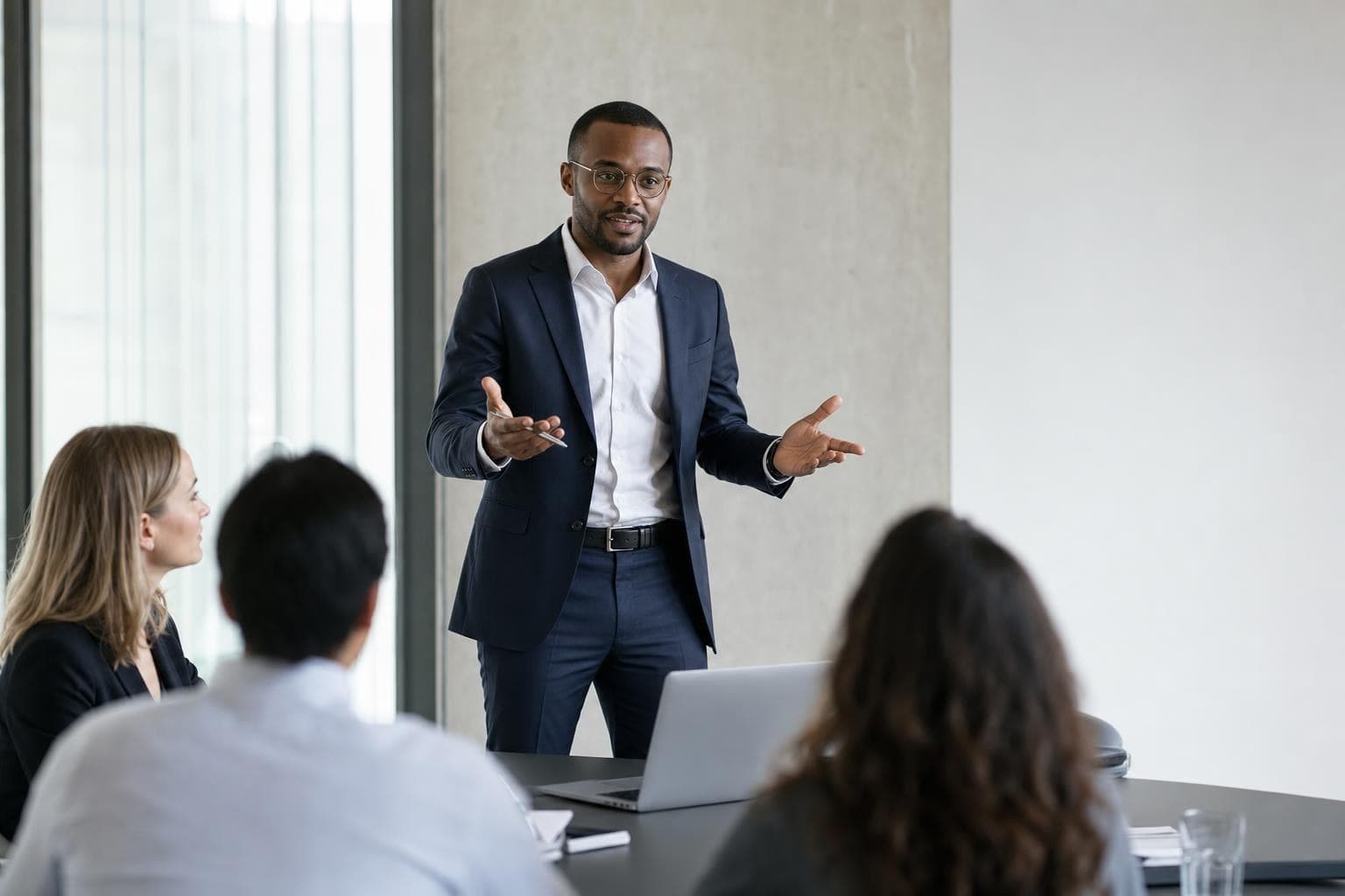 A sharply-dressed solo consultant confidently presenting to a small client group in a crisp office.