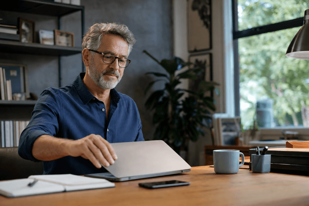 An owner closing a laptop with a calm, confident expression in a tidy office.
