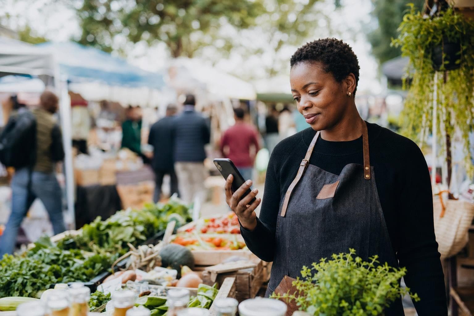 An owner testing his website on a phone outdoors at a market stall.