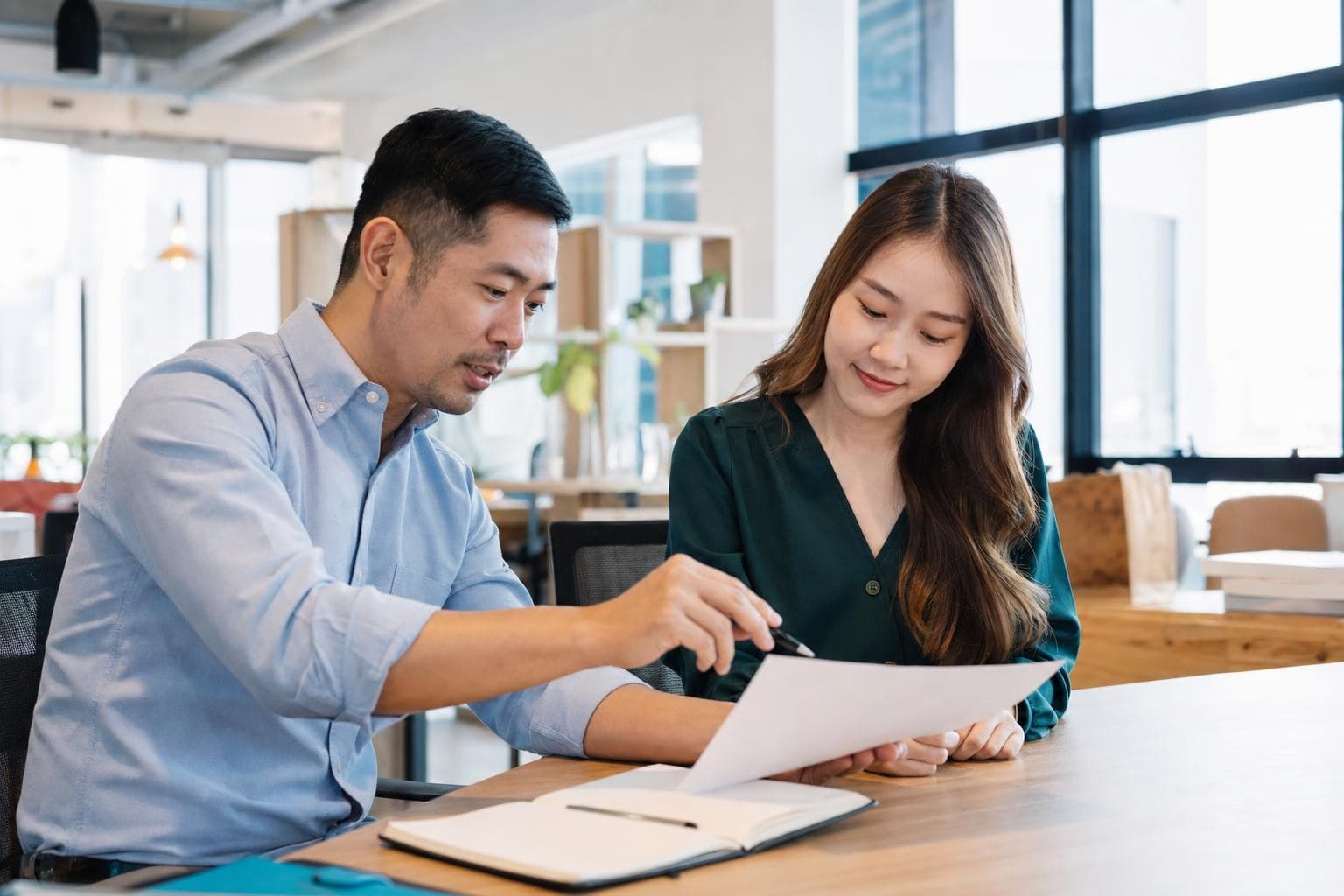 A photo of an owner warmly training a new employee with a clear guide in a bright workplace.