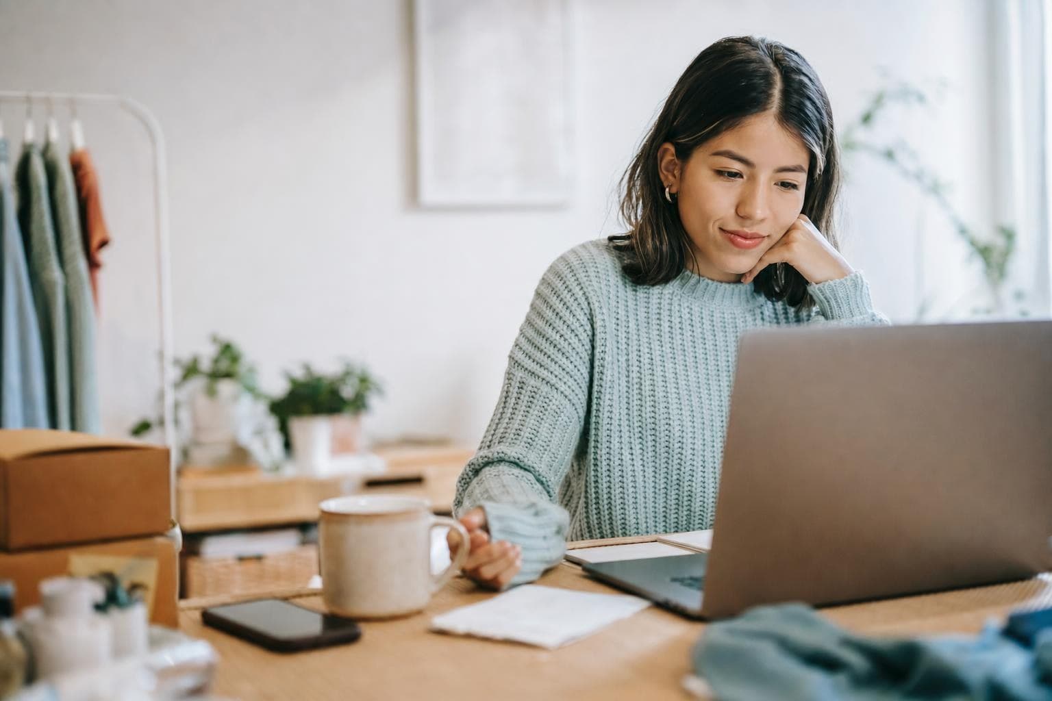 An online-shop owner drafting a newsletter at a cozy desk with a coffee.