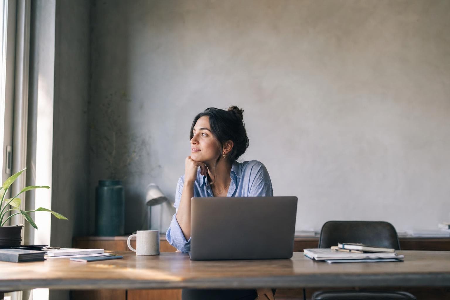 A person hopeful at a desk weighing a big career decision in morning light.