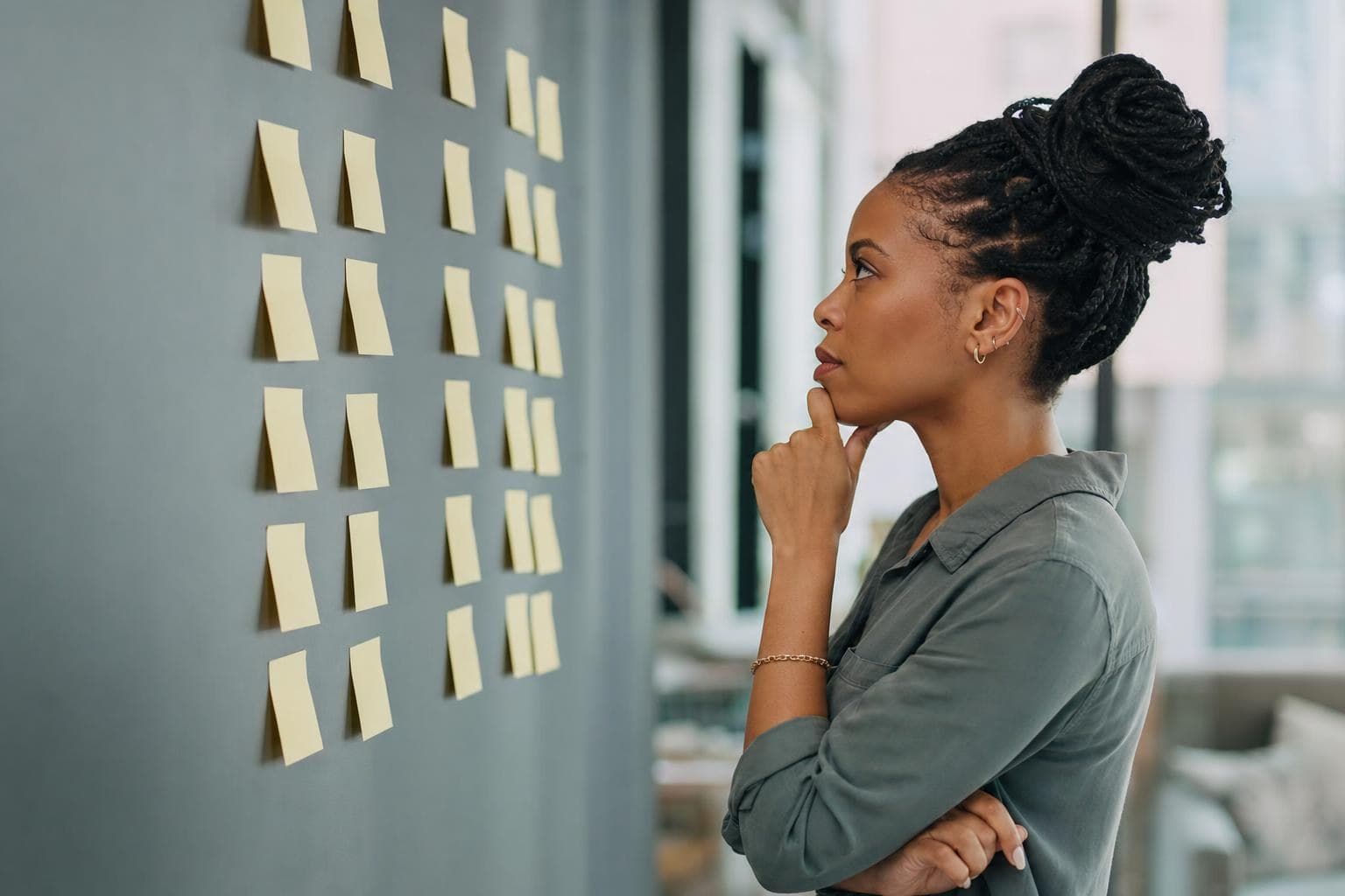 An owner looking at a wall of sticky-note tasks deciding what to delegate.