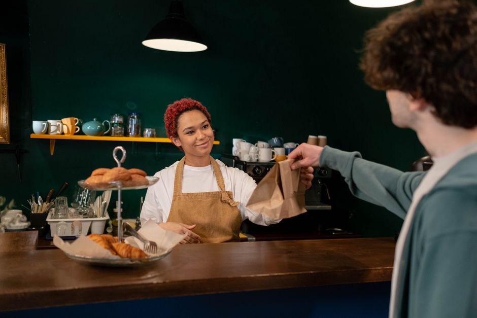 Bakery owner serving a pastry to a customer.