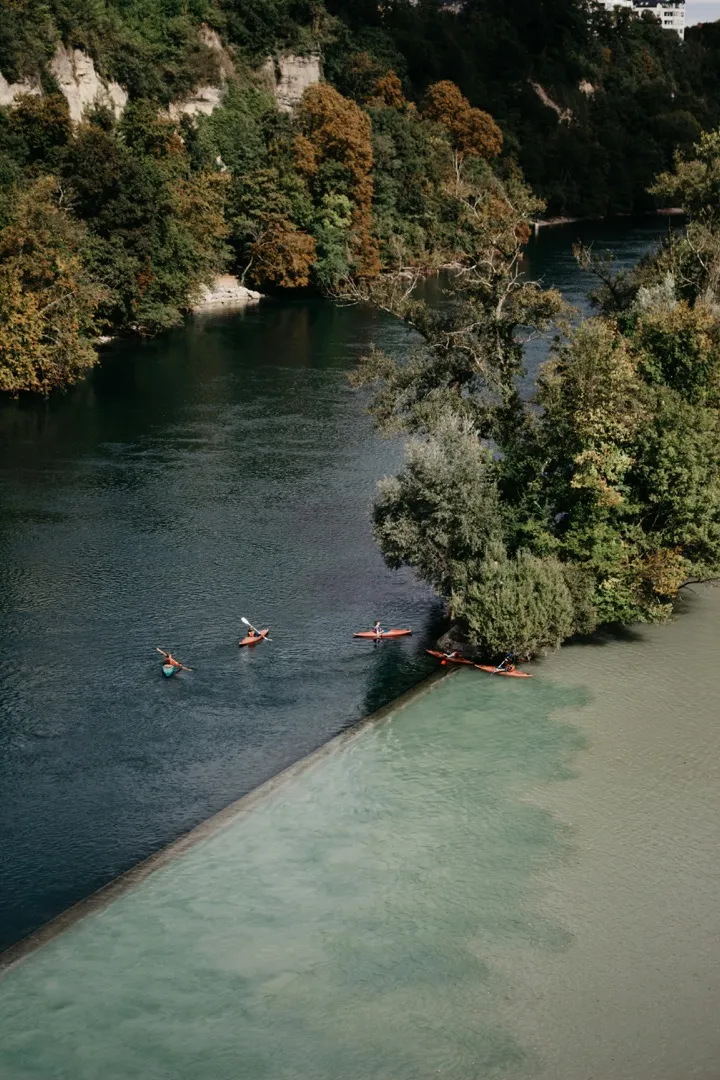 Two paddlers in separate kayaks moving through a narrow rocky channel