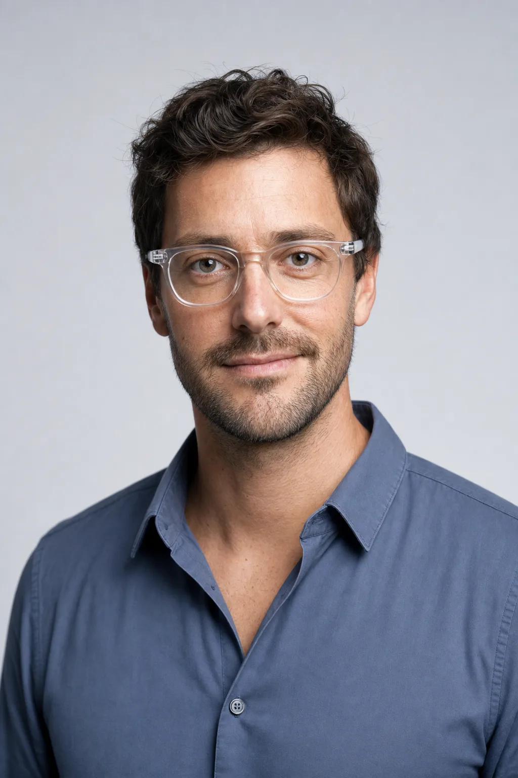 Elias Brandt, master optician, in crystal acetate glasses against a cool grey backdrop.